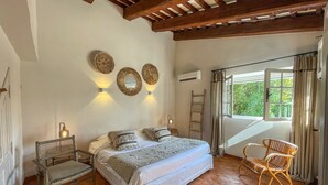 Un dormitorio con cama, dos sillas, una escalera y una ventana con cortinas.