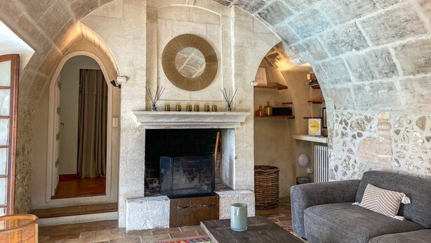 Una sala de estar con paredes de piedra, una chimenea, un sofá y una estantería.