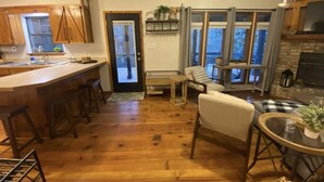 A spacious kitchen with wooden flooring, a bar area, and a seating area with a fireplace.