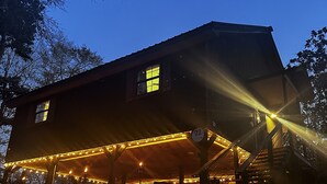 A two-story building with a covered porch and string lights.