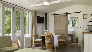 A cozy room with a dining table, chairs, a sofa, and a television. - Two dog friendly holiday properties with hot tub - Keepers Homes (Cranham)