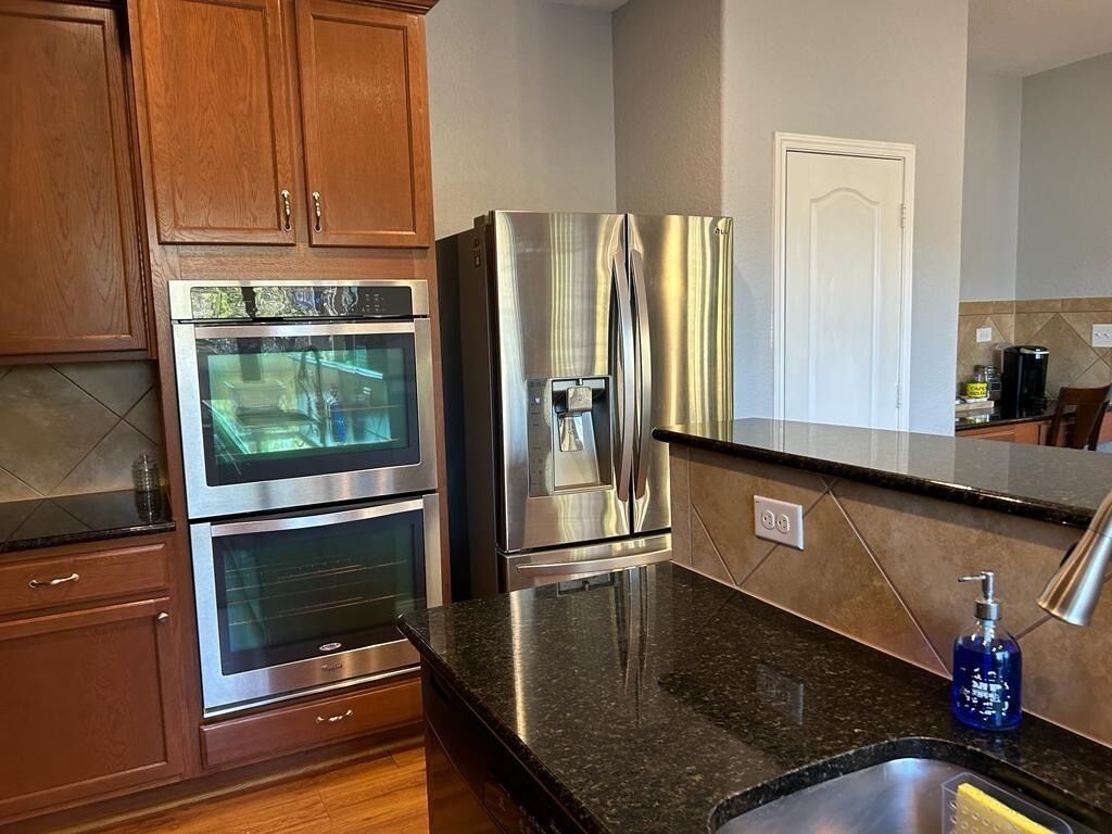 A kitchen with stainless steel appliances, wooden cabinets, and a granite countertop.
