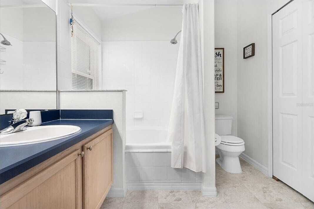 A bathroom with a white bathtub, a white toilet, and a sink with a dark countertop.