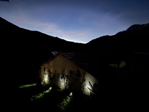 Ein Haus mit geneigtem Dach, umgeben von dunklen Hügeln.