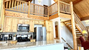 A spacious kitchen with wooden cabinets, a stainless steel refrigerator, and a microwave. - Cozy Cabin Escape: Nature, Comfort, and Serenity Await! (Grand Lake)