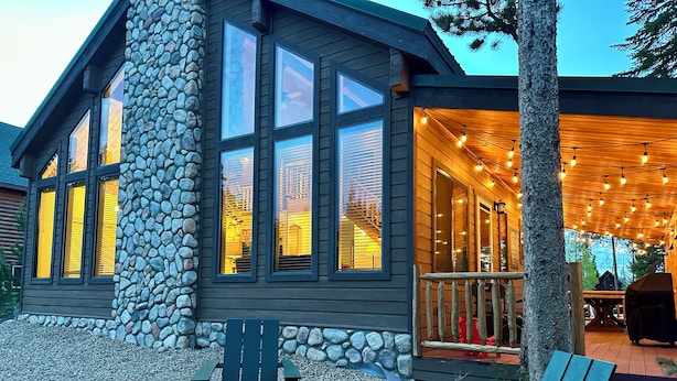 A cabin with a stone exterior, large windows, and a fire pit. - Cozy Cabin Escape: Nature, Comfort, and Serenity Await! (Grand Lake)