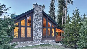 A cabin with a stone chimney, large windows, and a deck. - Cozy Cabin Escape: Nature, Comfort, and Serenity Await! (Grand Lake)