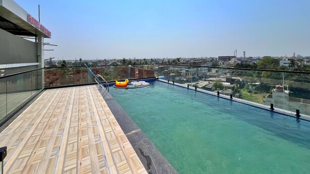 Una piscina en la azotea con agua azul cristalina, un patito inflable amarillo y vistas de la ciudad al fondo.