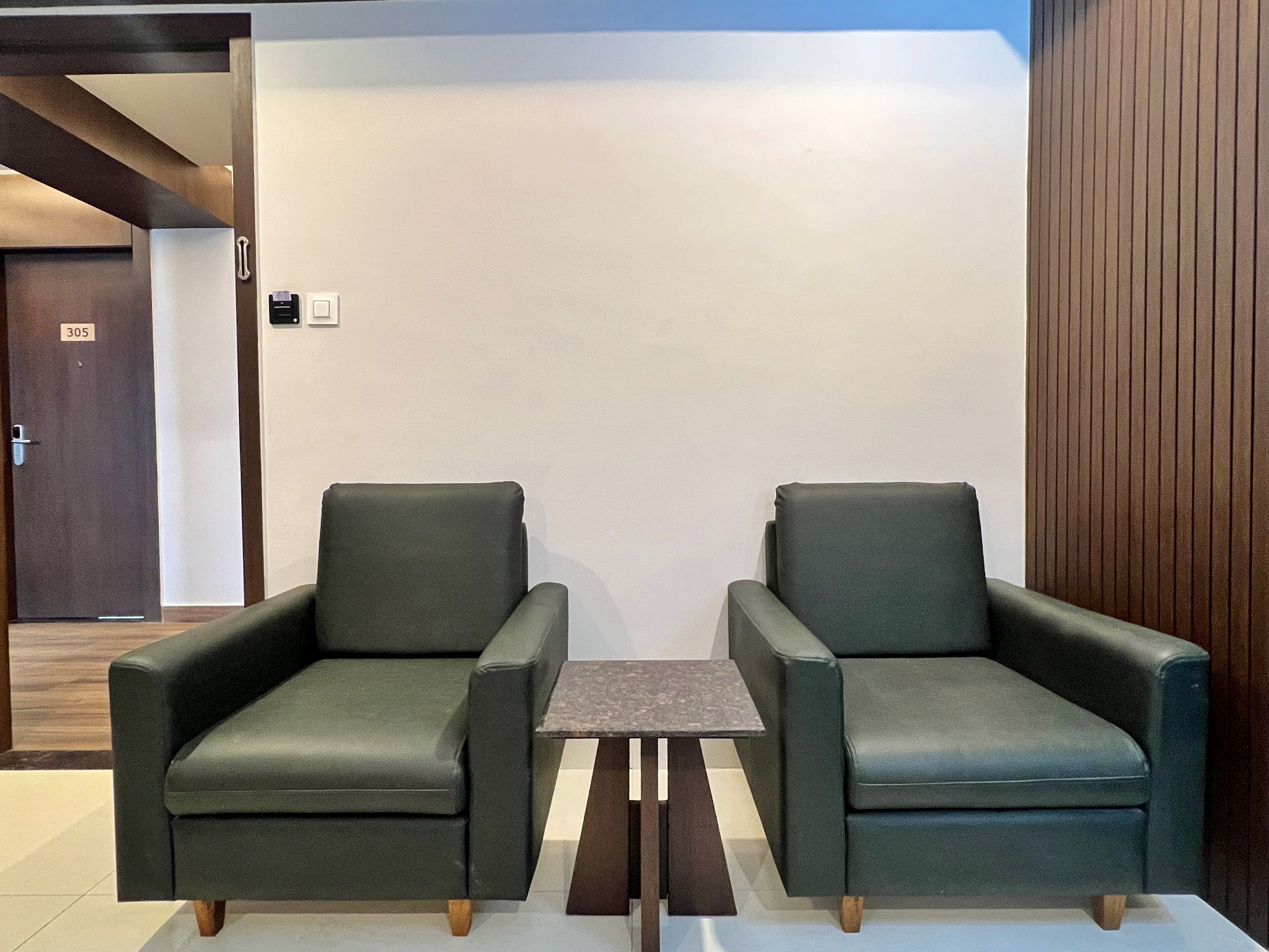 A room with two green armchairs and a small table in the center.