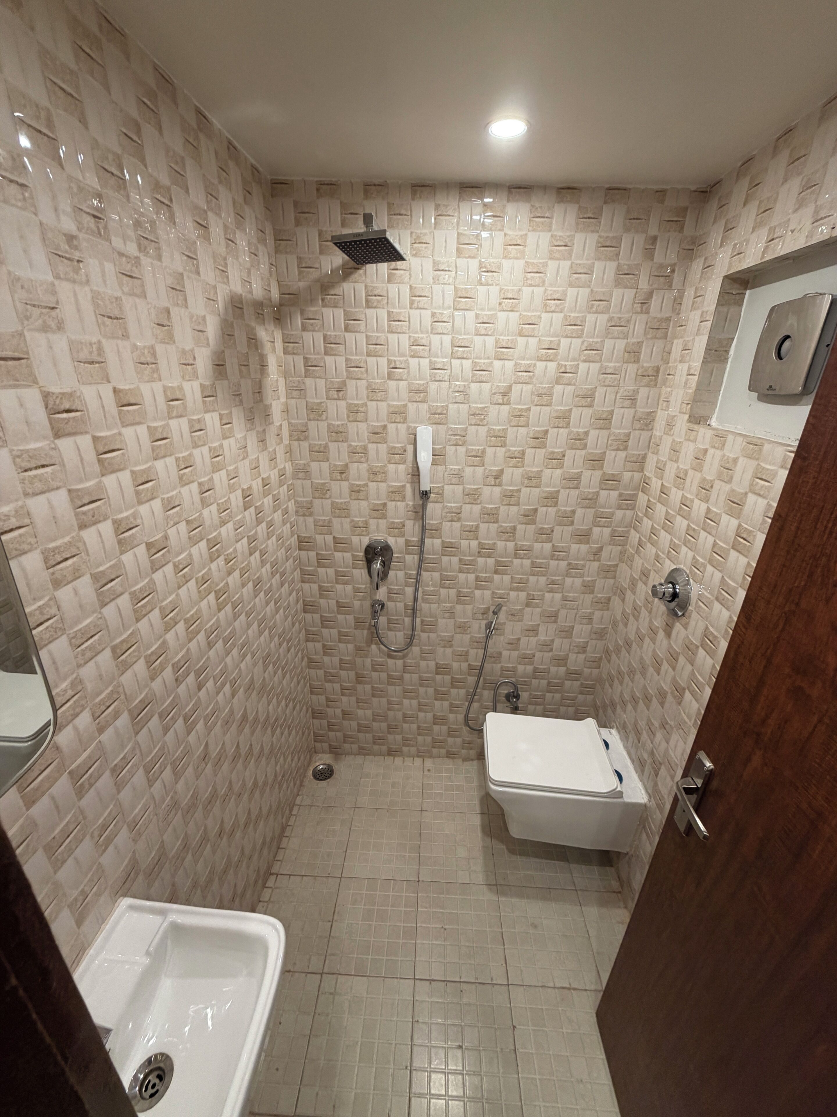 A small, tiled shower room with a toilet and a sink.