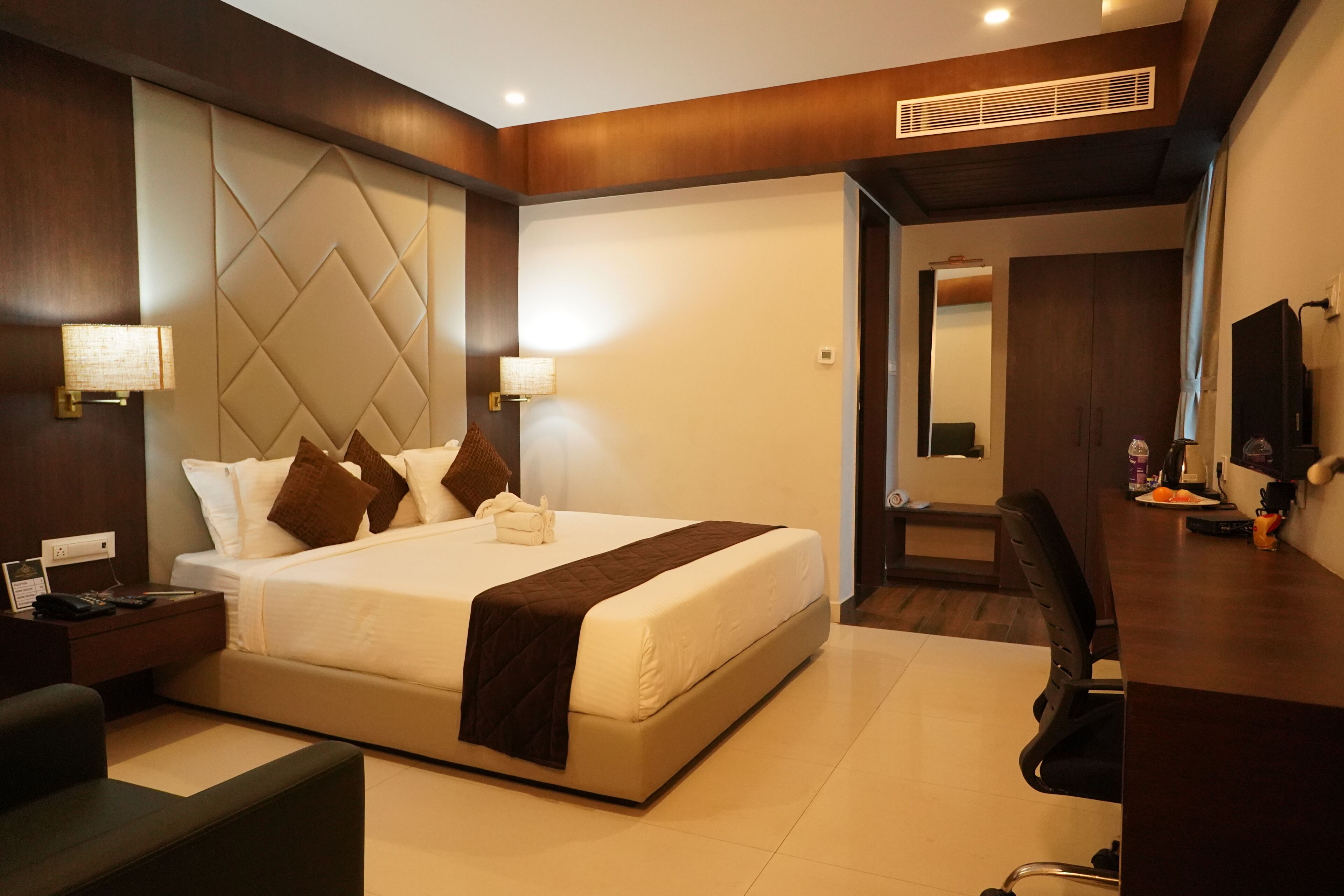 A modern hotel room with a large bed, bedside tables, a desk, and a chair.