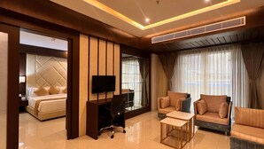 Una habitación de hotel moderna con una cama grande, televisión, escritorio y dos sofás.