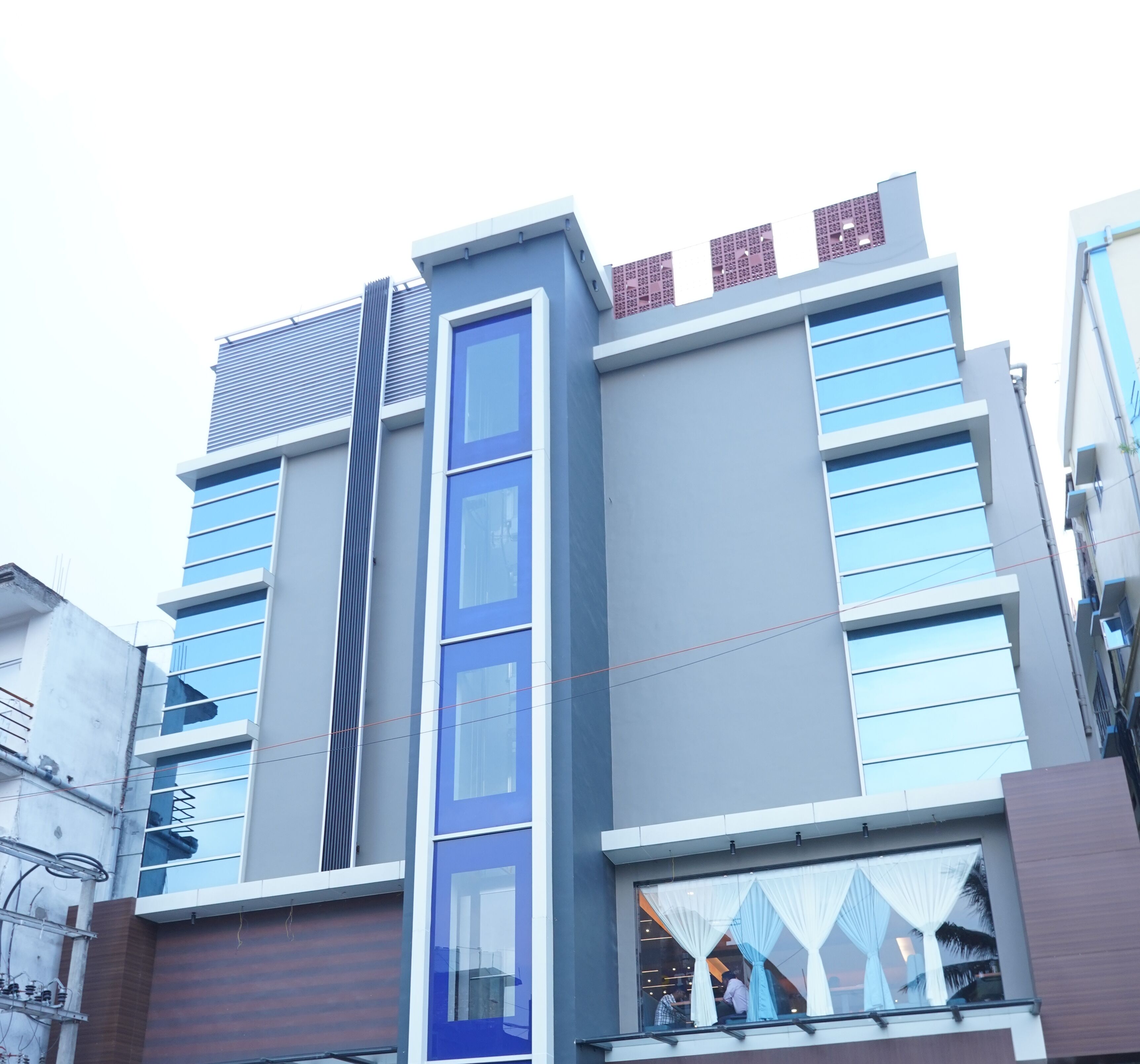 A modern building with a blue facade, large windows, and a visible entrance.