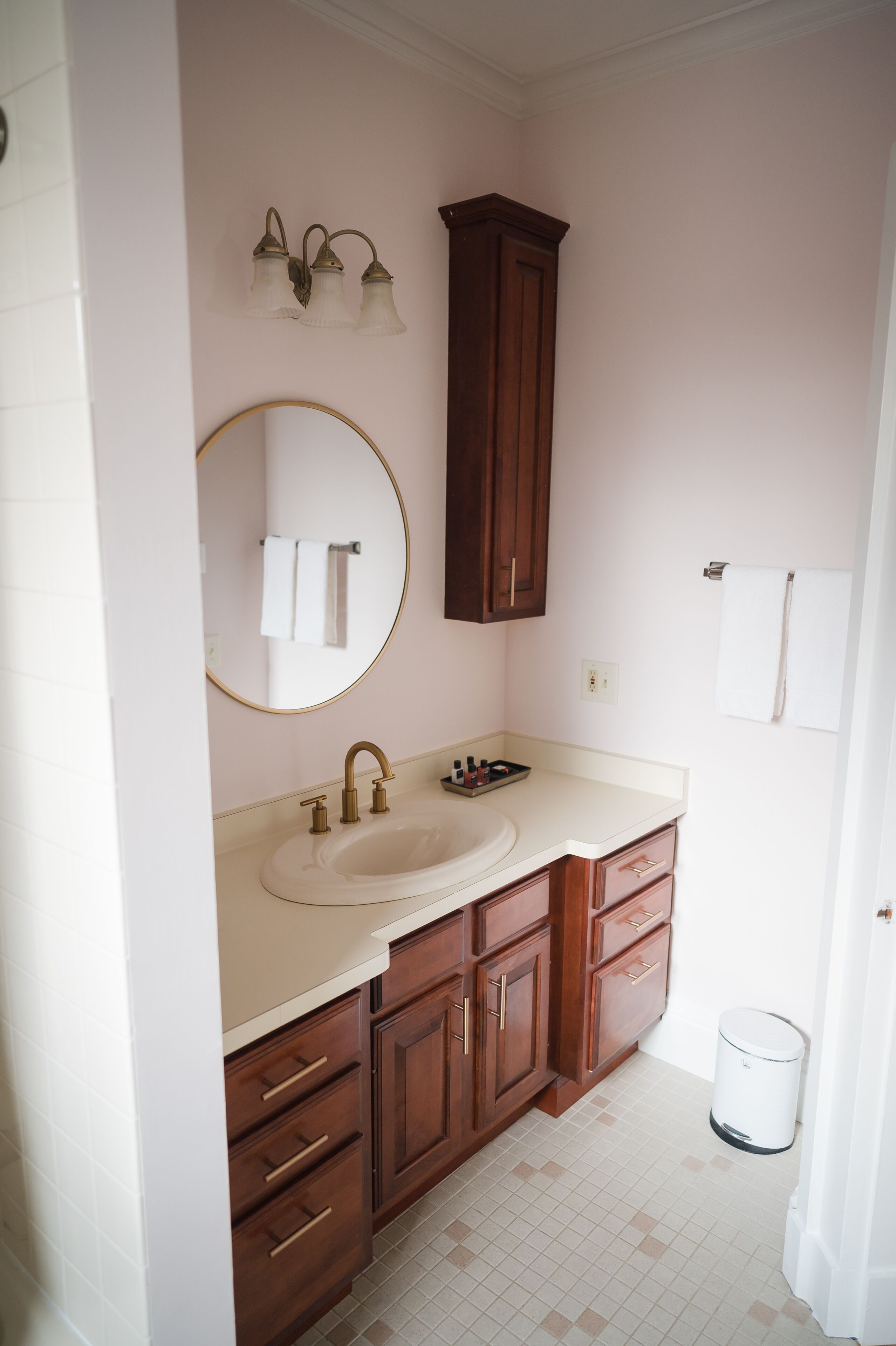A bathroom with a sink, mirror, vanity, and wooden cabinets.