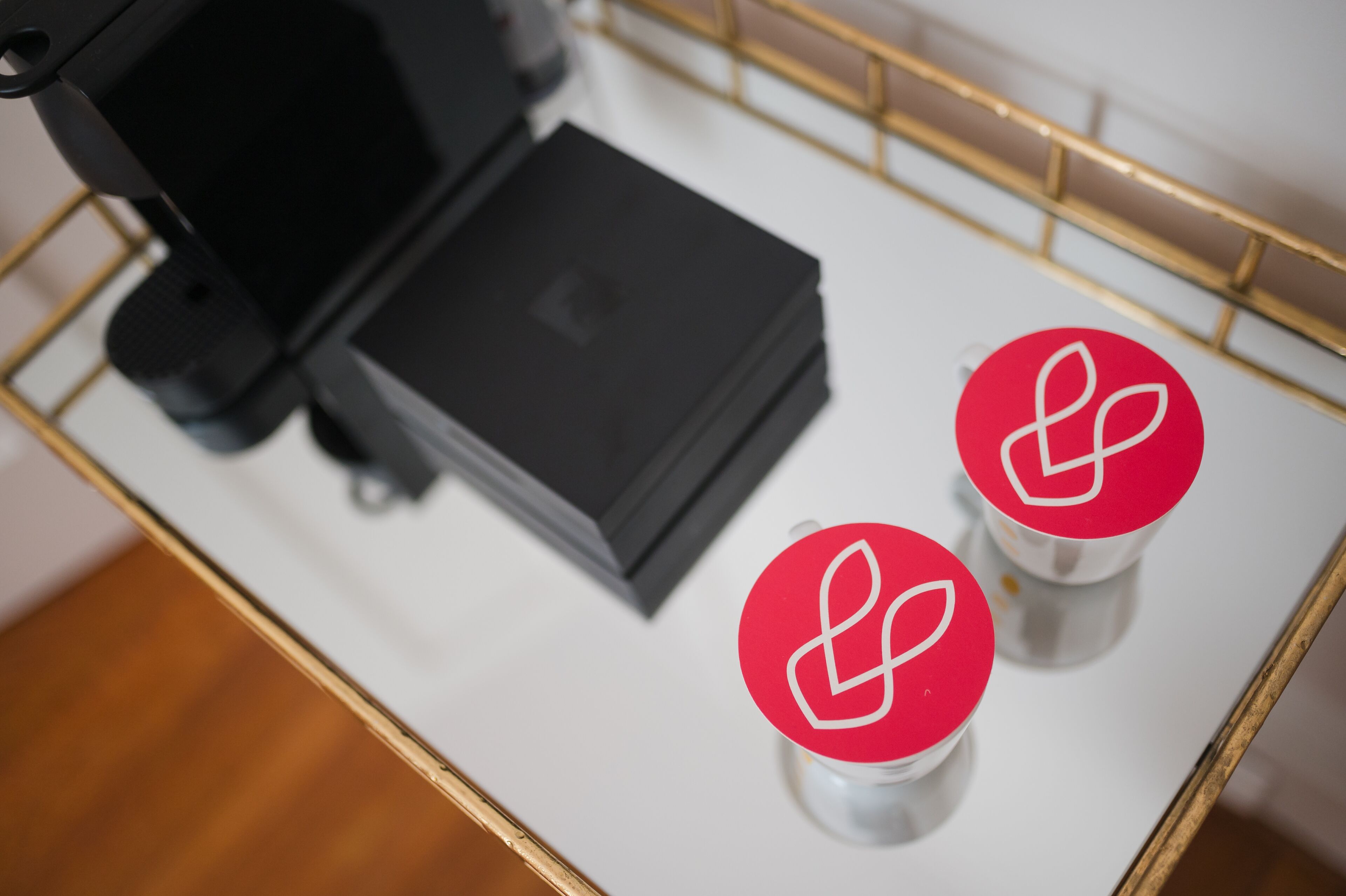 A coffee machine and two cups with red lids on a white tray.