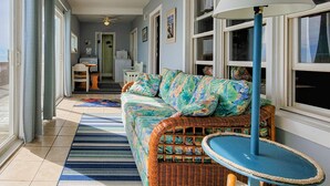 A sunlit room with a wicker sofa, a blue-striped rug, and a ceiling fan. - Virginia's Beach - Cozy Oceanfront Beach Cottage! (Surf City)