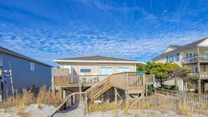 A beachfront house with a wooden deck and stairs leading to the entrance. - Virginia's Beach - Cozy Oceanfront Beach Cottage! (Surf City)