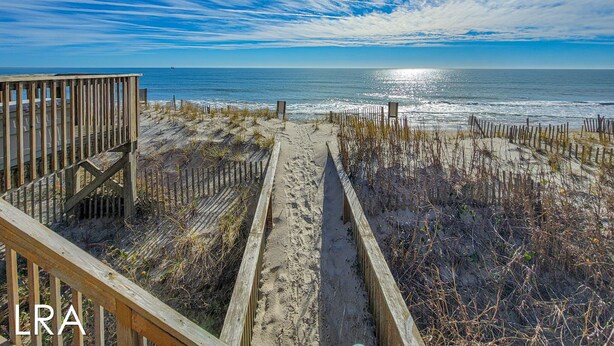 A wooden boardwalk leading to the beach with a clear view of the ocean and a ship in the distance. - Virginia's Beach - Cozy Oceanfront Beach Cottage! (Surf City)