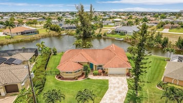 A residential property with a red-tiled roof, a swimming pool, and a well-maintained lawn.