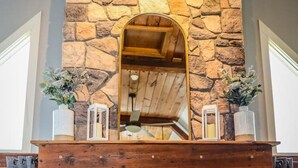 A stone fireplace with a wooden mantel, a mirror above it, and a fire burning inside.