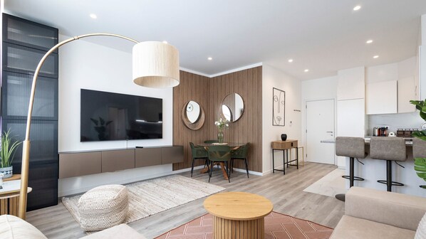 A modern living room with a large TV, dining area, kitchen, and a bar area.