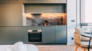 Una cocina moderna con salpicadero de mármol, horno empotrado y cafetera.