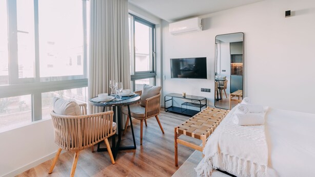 Una habitación de hotel moderna con comedor, televisión y un ventanal grande.