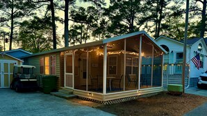A house with a covered porch, a golf cart, and a flag. - The Nautical Nook Beach Cottage - #1714 Ocean Lakes (Myrtle Beach)