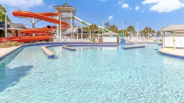 A swimming pool with a water slide and lounge chairs. - The Nautical Nook Beach Cottage - #1714 Ocean Lakes (Myrtle Beach)