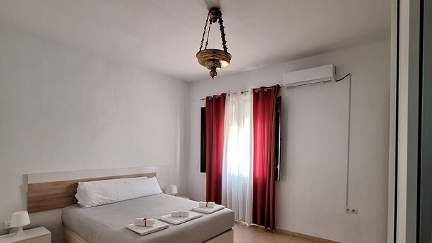 A modern bedroom with a bed, bedside table, and a hanging light fixture. - Feria Especial (Sevilla)