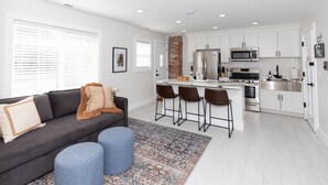 A modern kitchen with white cabinets, stainless steel appliances, and a central island with bar stools. - The Inn at Fulton (Sandusky)