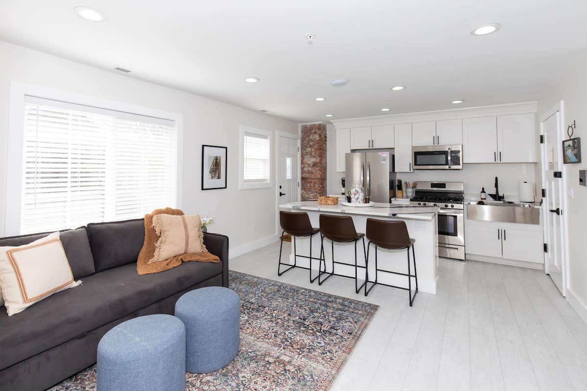 A modern kitchen with white cabinets, stainless steel appliances, and a central island with bar stools.