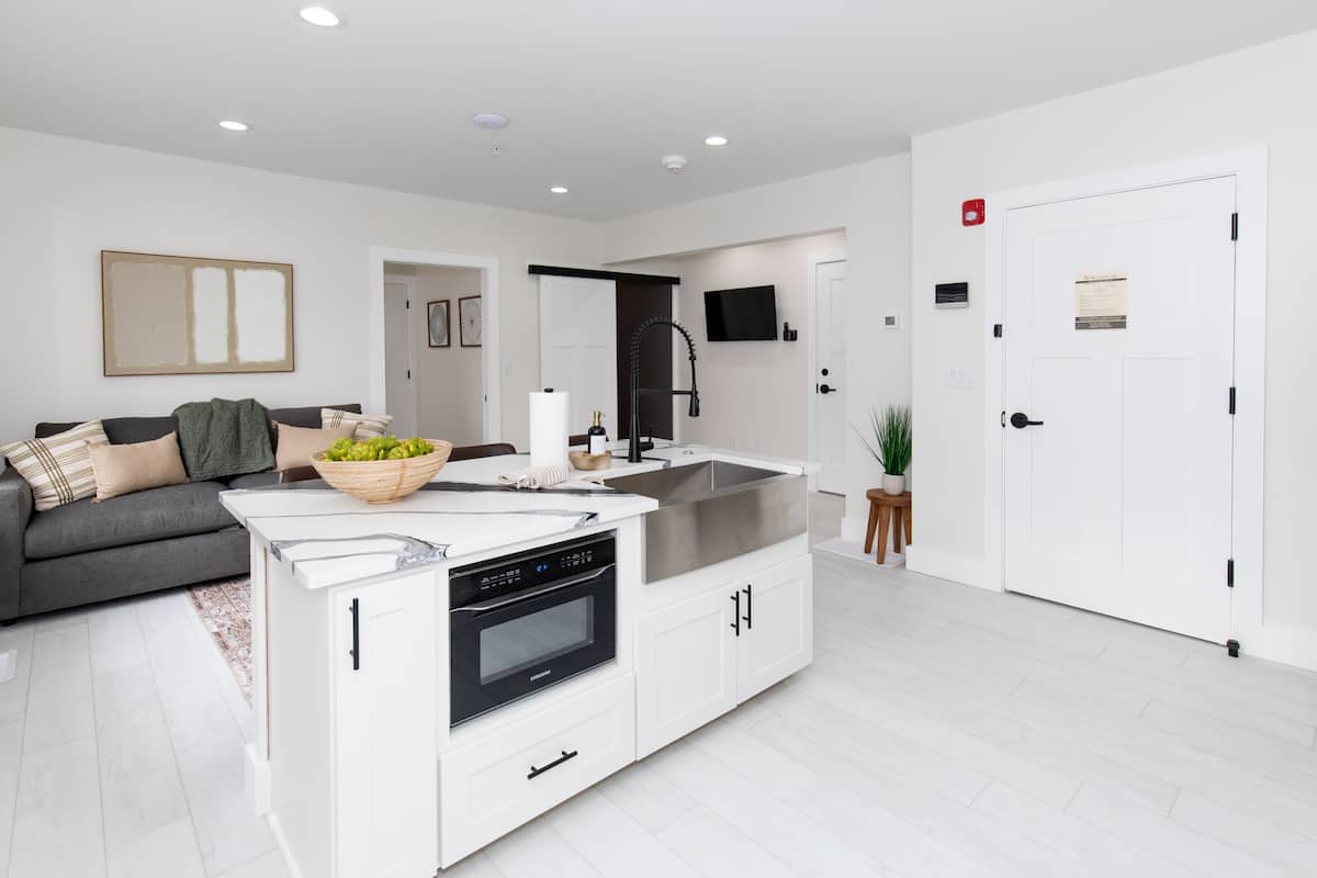 A modern kitchen with white cabinetry, a built-in oven, and a stainless steel sink.