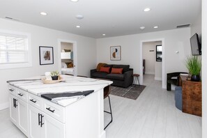 A modern kitchen with white cabinets, a marble countertop, and a built-in oven. - The Inn at Fulton (Sandusky)