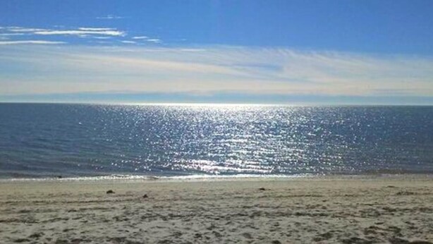 A beach with a clear sky and calm sea.