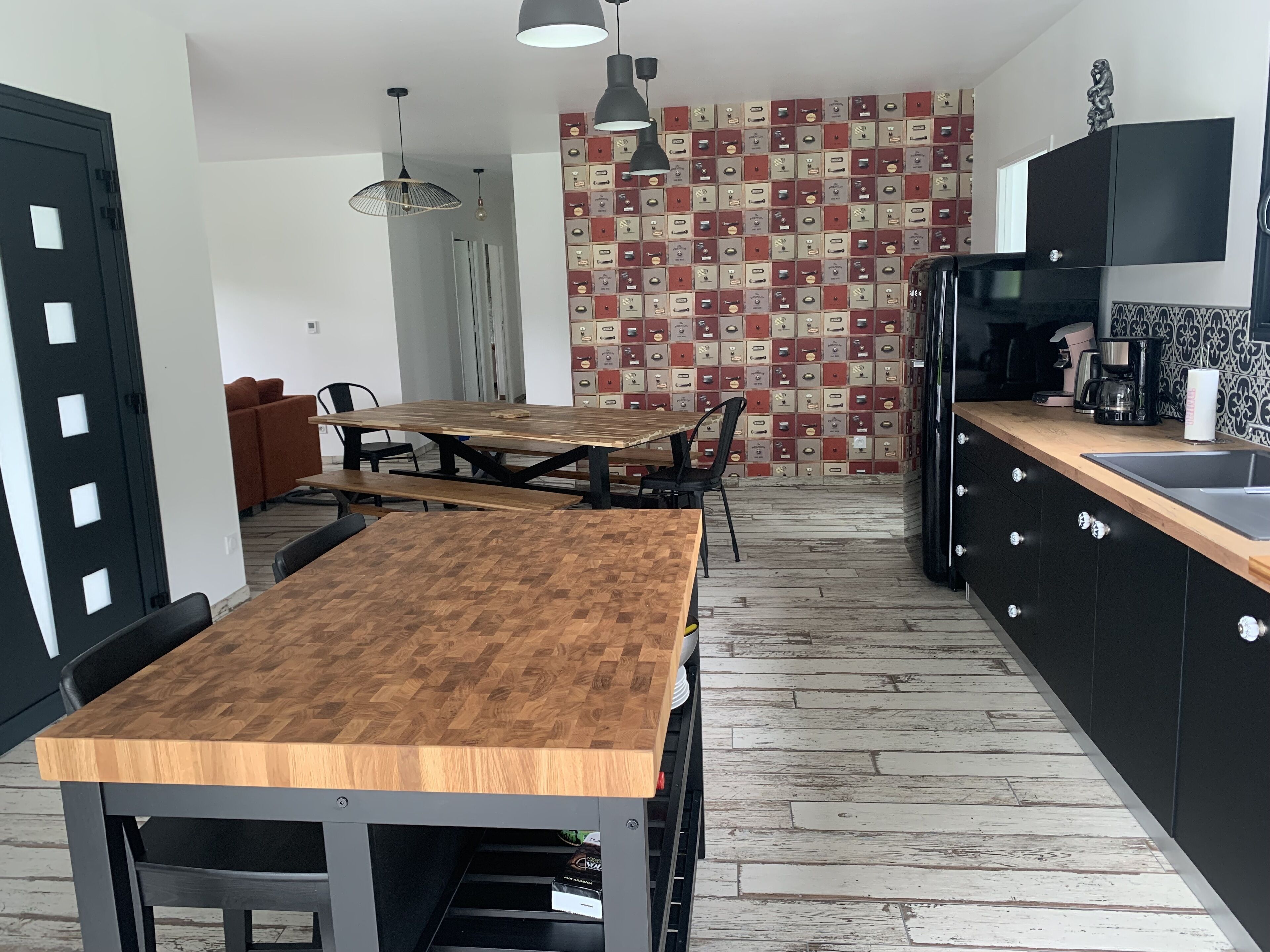 Una cocina moderna con una mesa de madera, armarios negros y una pared con diseño.