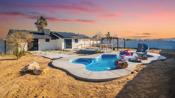 A modern house with a swimming pool, a hot tub, and a deck area.