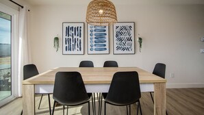 A dining area with a wooden table, black chairs, and three framed abstract artworks on the wall.