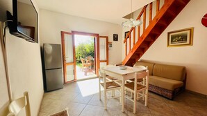 Un espacio habitable compacto con cocina, comedor y una escalera que lleva a un nivel superior.