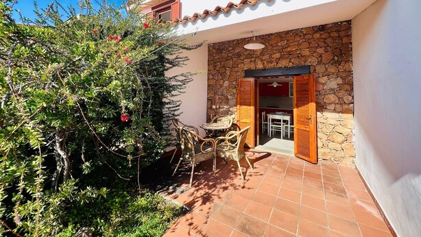 Un patio con un muro de piedra, una mesa y sillas.