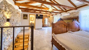 Ein Schlafzimmer mit einem hölzernen Bett, Steinwänden, einer Treppe und einer Holzbalkendecke.