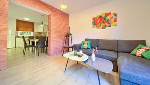 A modern living room with a grey sofa, a small white coffee table, and a dining area with a table and chairs. - Holiday apartment with terrace near the beach (Vrbnik)