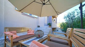 An outdoor seating area with wooden benches and a large umbrella. - Holiday apartment with terrace near the beach (Vrbnik)