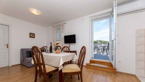 Un coin repas avec une table ronde, des chaises en bois et un téléviseur fixé au mur.