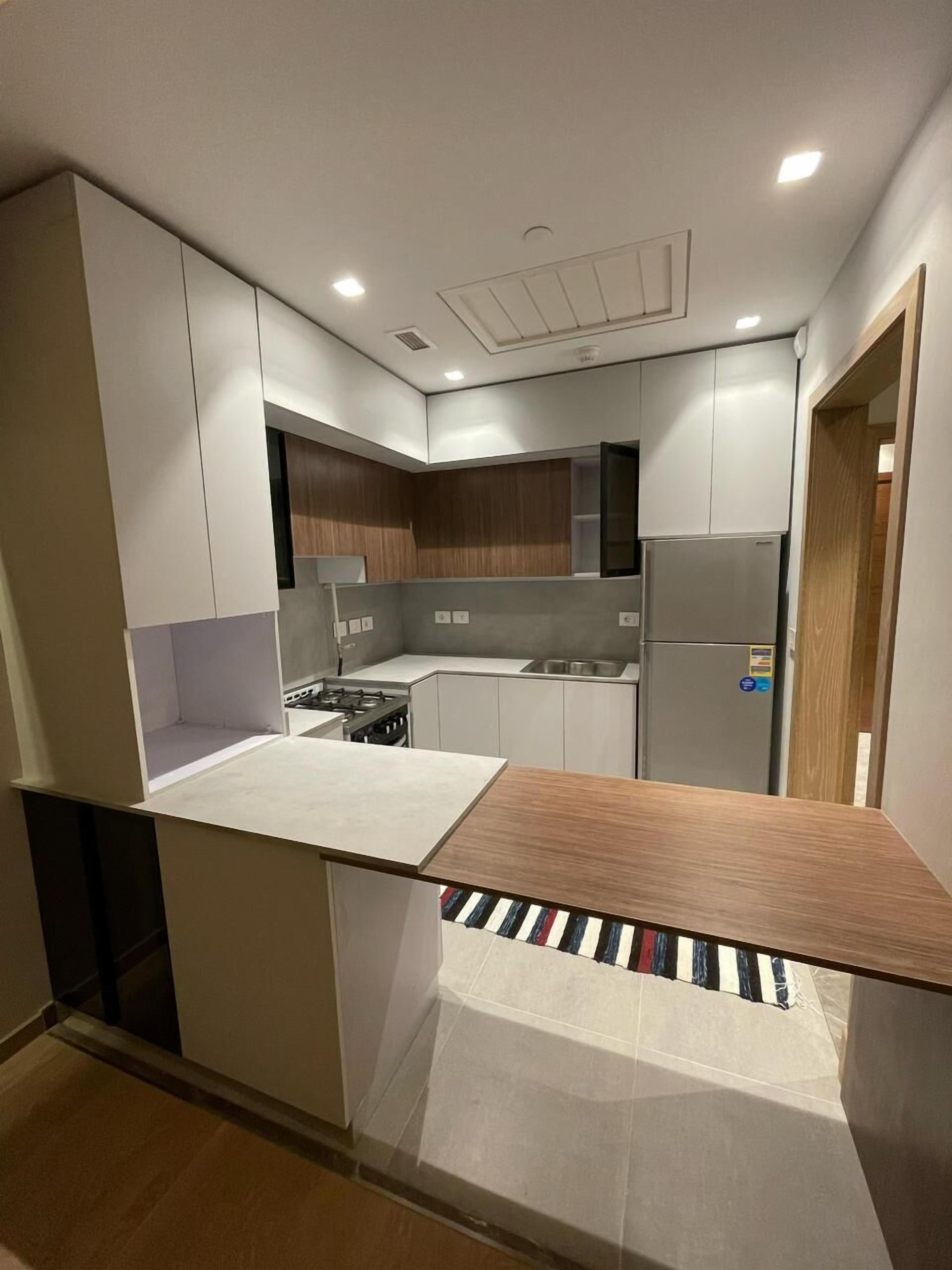 Una cocina moderna con armarios blancos, estufa integrada y refrigerador de acero inoxidable.