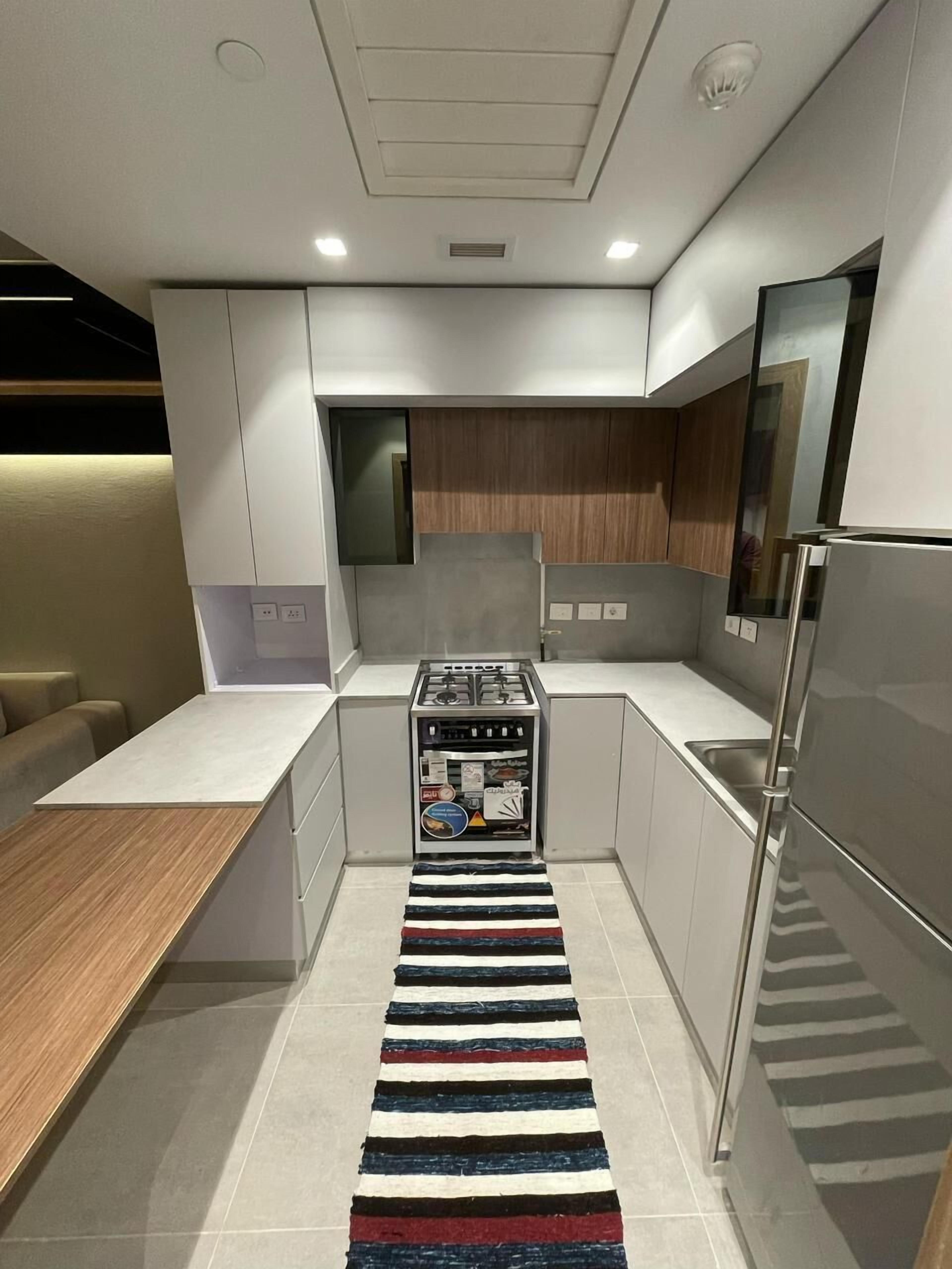 A modern kitchen with a central island, built-in appliances, and a striped rug.