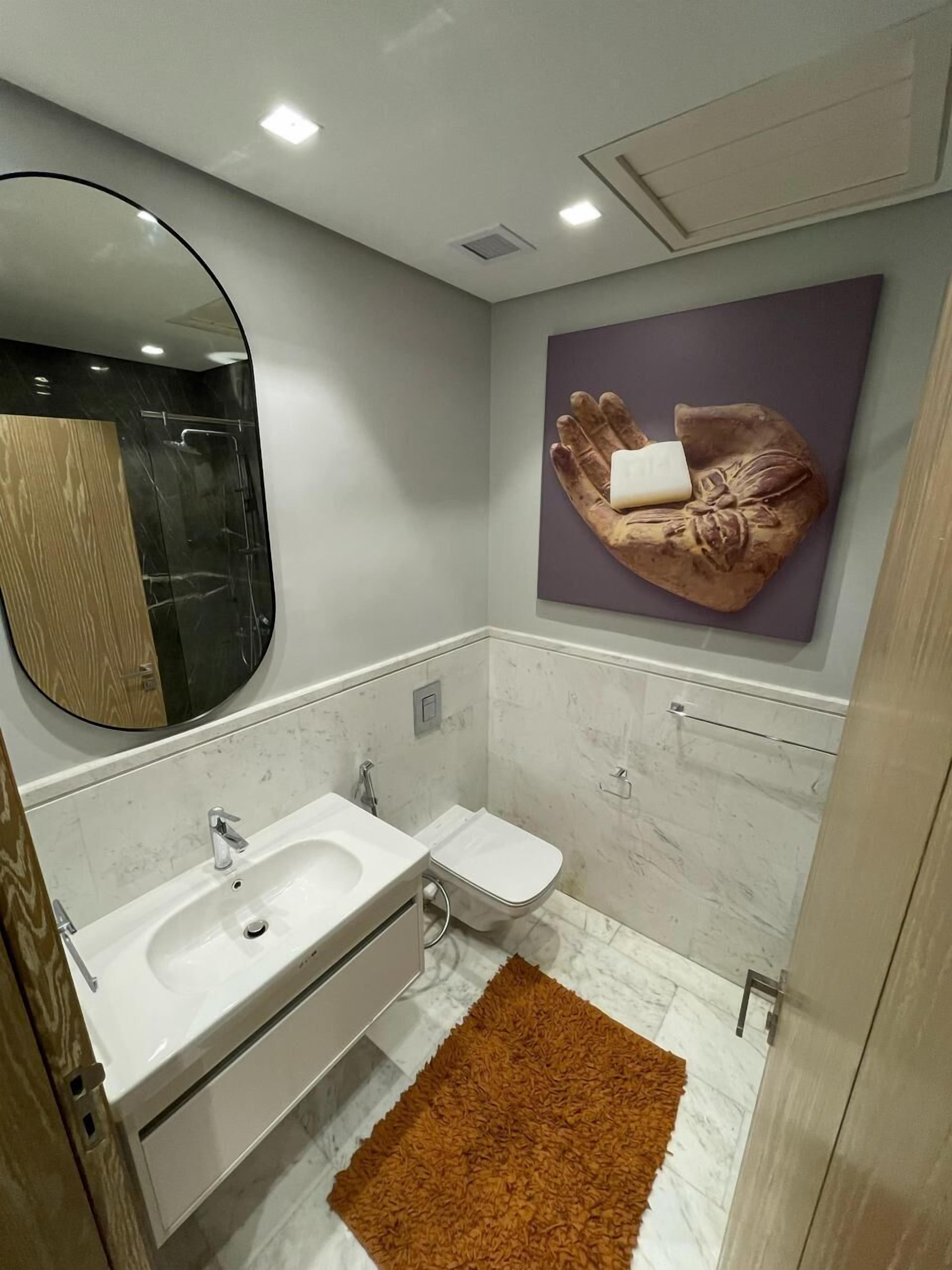 A modern bathroom with a white sink, mirror, and a towel rack.