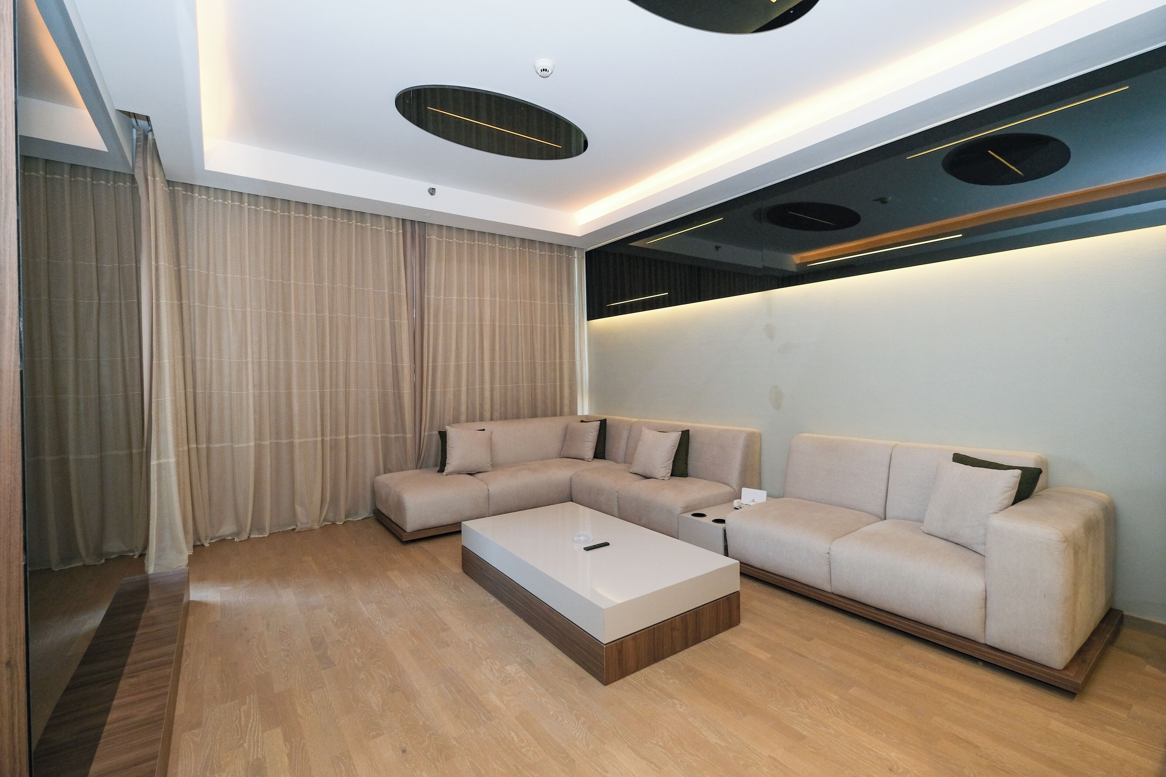 Una sala de estar moderna con un sofá seccional, una mesa de centro y un ventanal con cortinas.