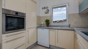 Eine moderne Küche mit Backofen von Bosch, Geschirrspüler und einem Fenster mit Blick auf Häuser.