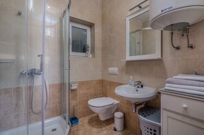 Une salle de bain avec une douche à parois de verre, des toilettes, un lavabo et un porte-serviettes.